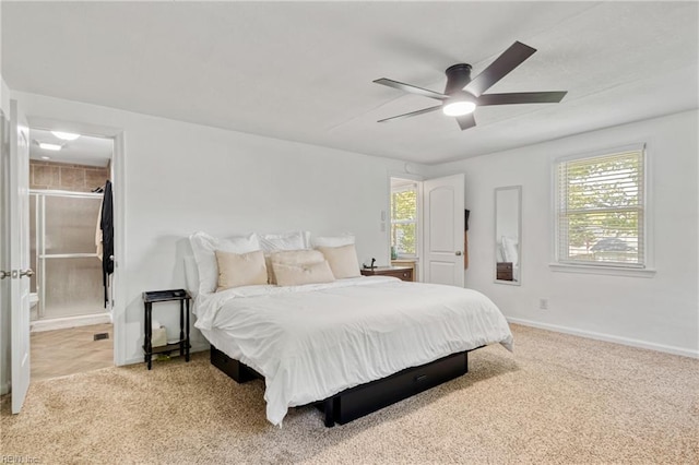 bedroom featuring baseboards, ensuite bathroom, a ceiling fan, and light colored carpet