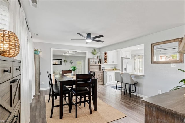 dining room featuring baseboards, a ceiling fan, light wood finished floors, and visible vents