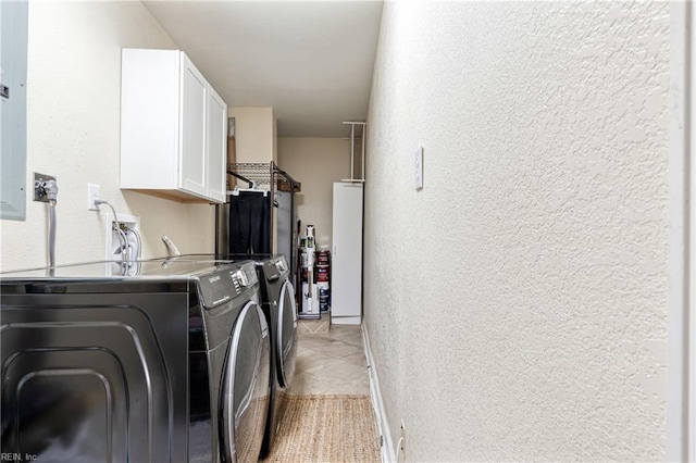 clothes washing area featuring cabinet space, a textured wall, washing machine and dryer, and light tile patterned floors