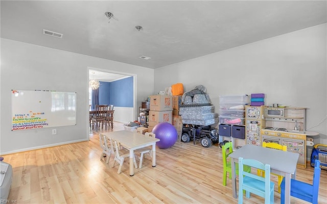 rec room featuring baseboards, wood finished floors, and visible vents