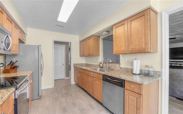 kitchen with visible vents, light stone countertops, light wood-style floors, a sink, and stainless steel appliances