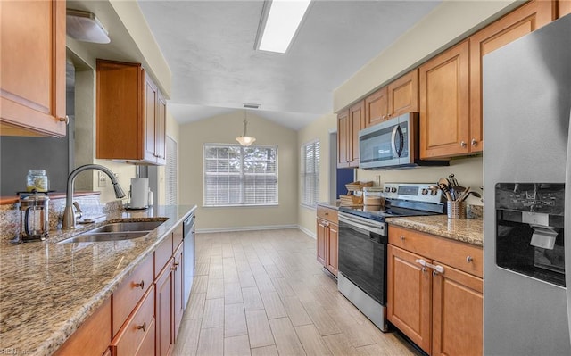 kitchen featuring a sink, appliances with stainless steel finishes, light stone countertops, and brown cabinetry