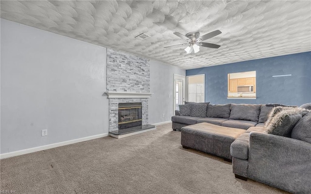 living area with carpet flooring, a stone fireplace, a ceiling fan, baseboards, and visible vents