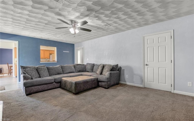 carpeted living area featuring baseboards and a ceiling fan