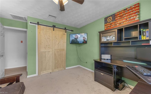 office area with baseboards, a ceiling fan, a barn door, and visible vents