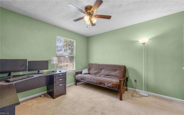 office space with light colored carpet, a ceiling fan, and baseboards