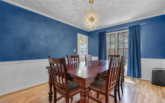 dining room with an inviting chandelier, baseboards, ornamental molding, and wood finished floors