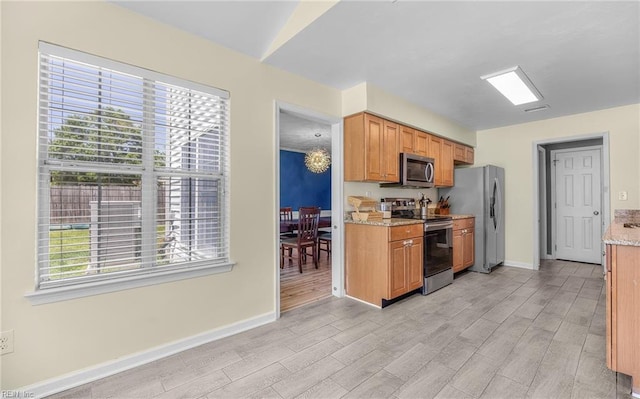 kitchen featuring appliances with stainless steel finishes, baseboards, light stone countertops, and light wood finished floors