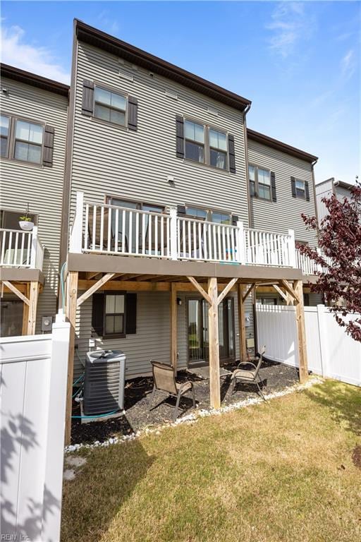 back of property with fence, a yard, a wooden deck, a carport, and cooling unit