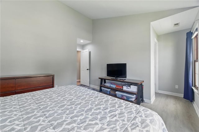 bedroom with baseboards, wood finished floors, and visible vents