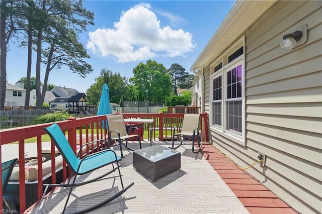 deck with a fenced backyard and a trampoline