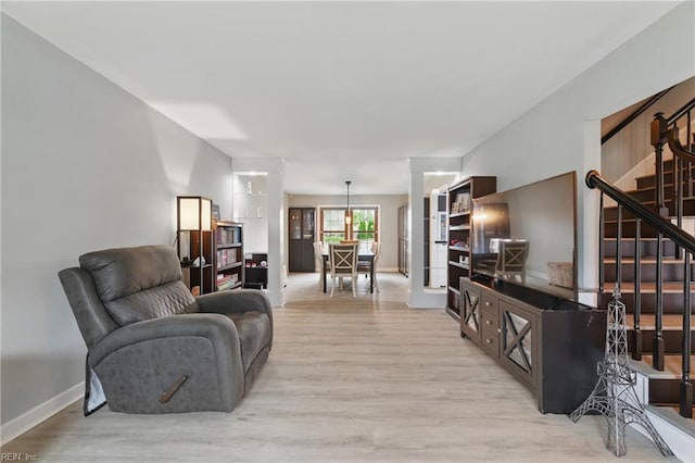 living area featuring baseboards, stairs, and wood finished floors