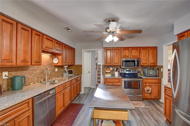 kitchen with a sink, stainless steel appliances, decorative backsplash, dark wood-type flooring, and visible vents
