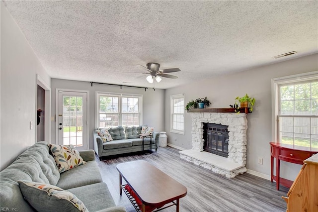 living room featuring a textured ceiling, ceiling fan, and wood finished floors