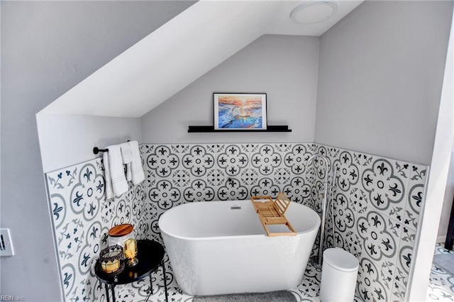 bathroom featuring tile walls, vaulted ceiling, and a soaking tub
