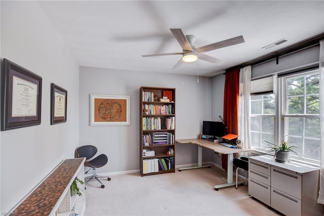 office space featuring visible vents, baseboards, ceiling fan, and light colored carpet