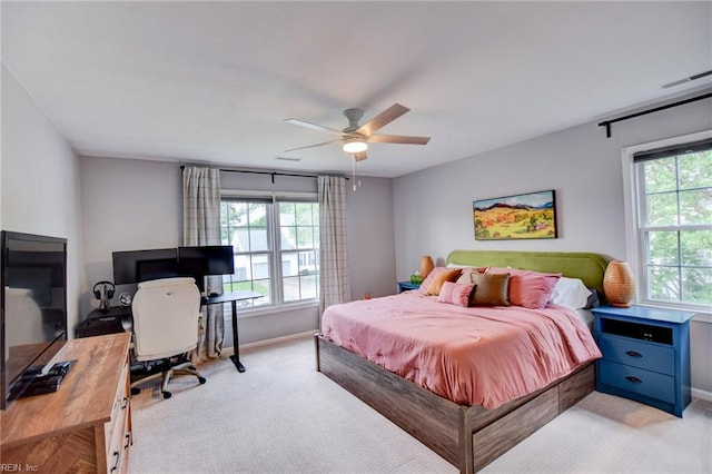 bedroom featuring baseboards, light carpet, and multiple windows
