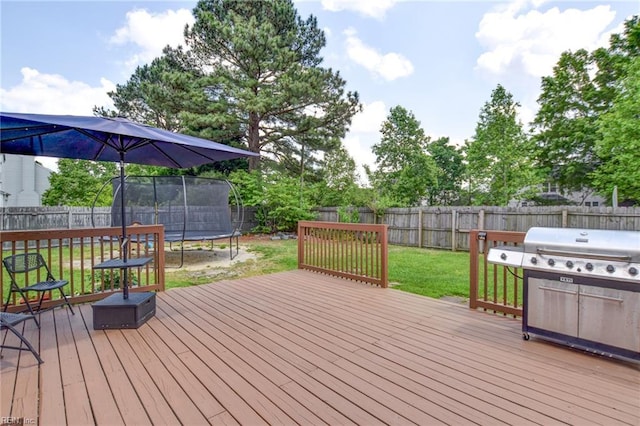 deck featuring a lawn, grilling area, a trampoline, and a fenced backyard