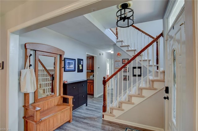 stairway with an inviting chandelier and wood finished floors