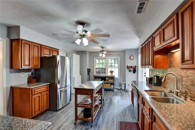 kitchen with visible vents, decorative backsplash, brown cabinets, a sink, and appliances with stainless steel finishes
