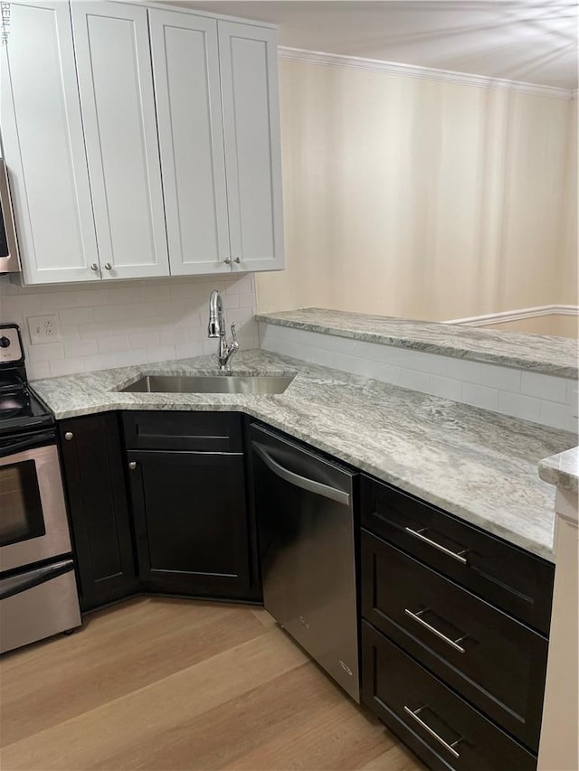 kitchen featuring crown molding, a sink, stainless steel appliances, white cabinetry, and light wood-type flooring