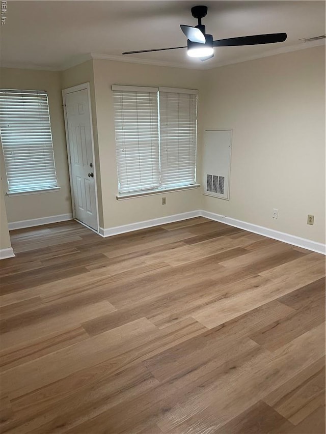 unfurnished room with visible vents, ornamental molding, wood finished floors, baseboards, and ceiling fan