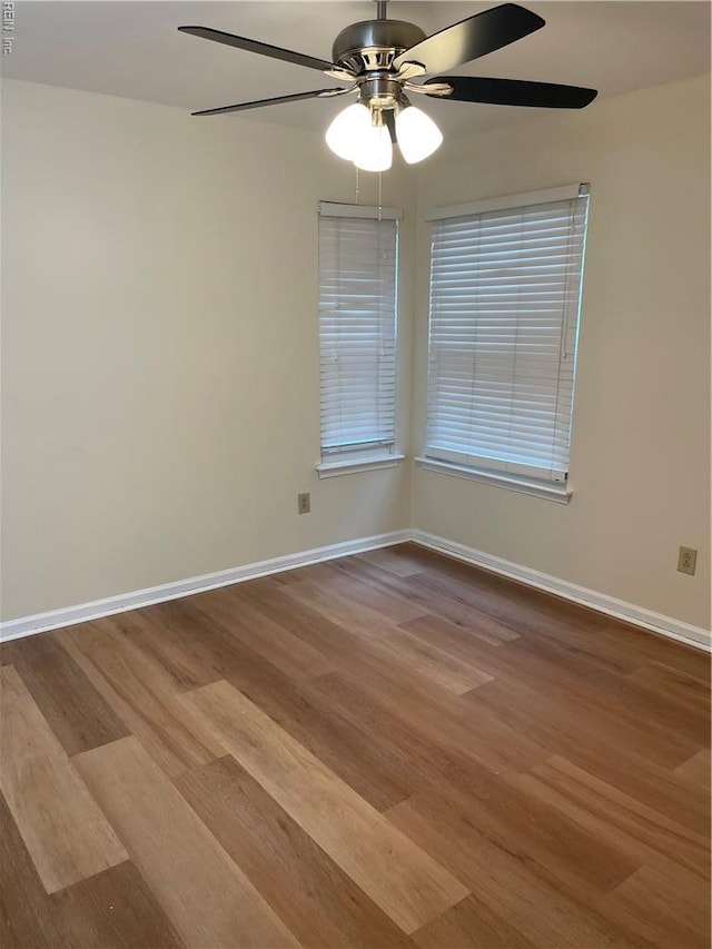 empty room featuring baseboards, ceiling fan, visible vents, and wood finished floors