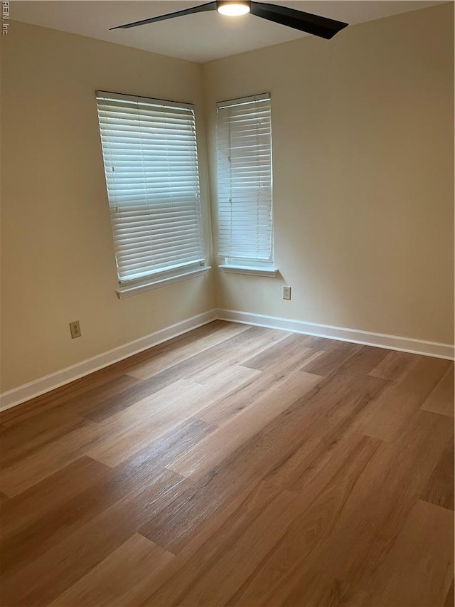 empty room with baseboards, ceiling fan, and wood finished floors