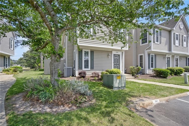 view of front of home featuring uncovered parking, cooling unit, and a front lawn