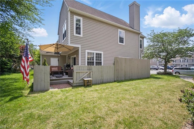 back of property featuring a chimney, a lawn, a wooden deck, fence, and an outdoor hangout area