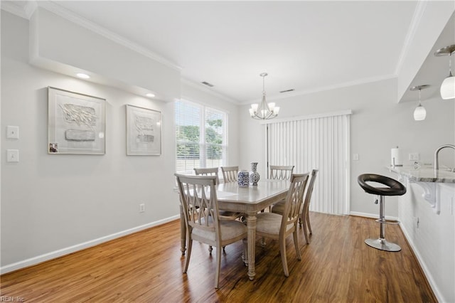 dining area featuring crown molding, baseboards, a chandelier, and wood finished floors