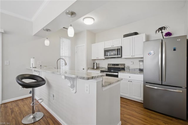 kitchen with crown molding, a breakfast bar area, stainless steel appliances, white cabinetry, and a peninsula