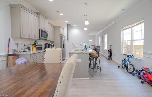 810 Fairland Ave, Hampton, VA 23661 - kitchen featuring light wood-style floors, a kitchen breakfast bar, stainless steel appliances, decorative backsplash, and ornamental molding