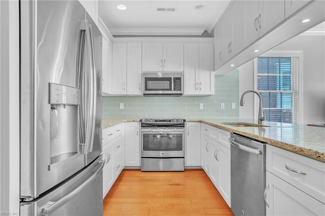 kitchen featuring visible vents, crown molding, a sink, white cabinets, and stainless steel appliances
