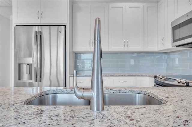 kitchen featuring backsplash, stainless steel appliances, and white cabinetry