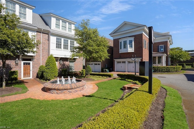 view of front of home with an attached garage, a front yard, driveway, and brick siding