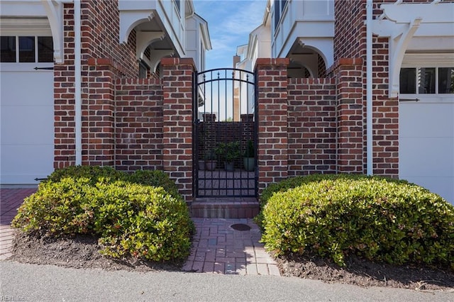 exterior space with brick siding, an attached garage, and a gate