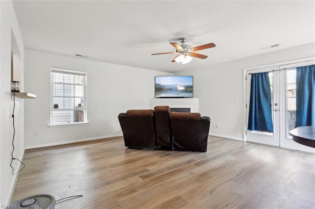 living room with baseboards, ceiling fan, wood finished floors, and visible vents