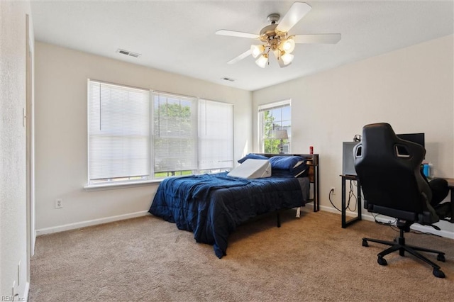 carpeted bedroom featuring baseboards, a ceiling fan, and visible vents
