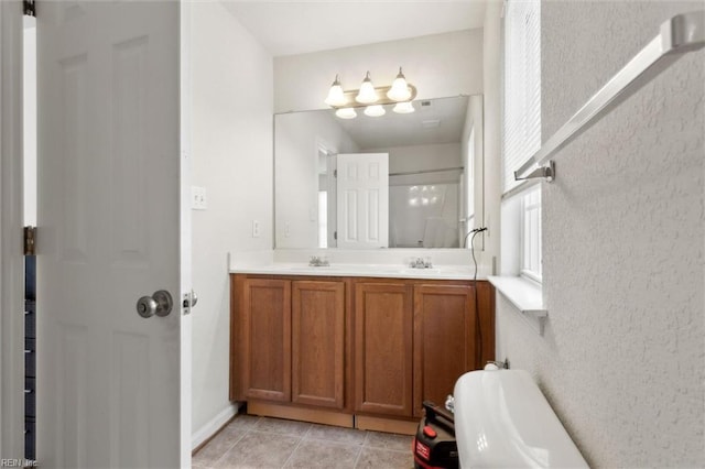full bathroom with double vanity, tile patterned floors, and a sink