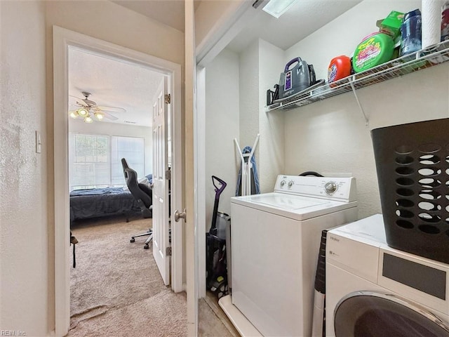 clothes washing area with washing machine and clothes dryer, laundry area, light colored carpet, a textured wall, and a ceiling fan