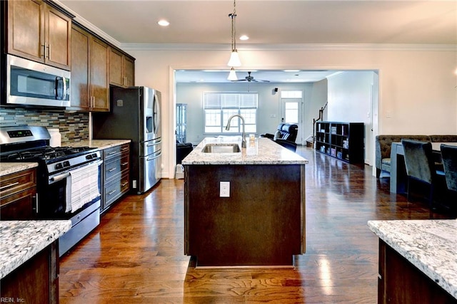 kitchen with a center island with sink, dark wood finished floors, a sink, open floor plan, and stainless steel appliances