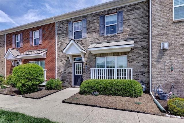 townhome / multi-family property with brick siding and a standing seam roof