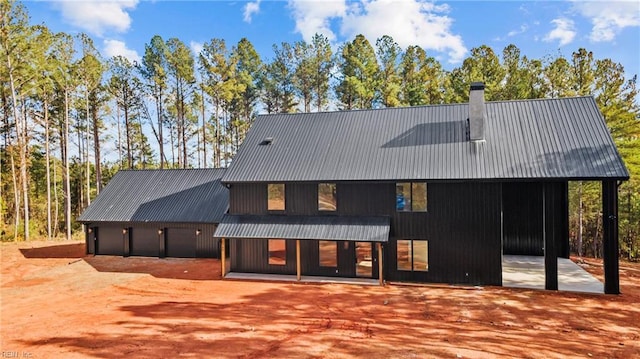 back of property featuring a garage, metal roof, and a chimney