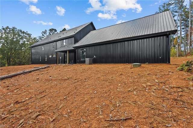 rear view of property featuring central AC unit and metal roof