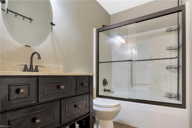 bathroom with toilet, vanity, and combined bath / shower with glass door
