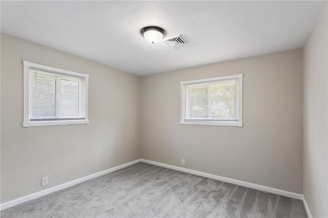 spare room featuring carpet floors, baseboards, and visible vents