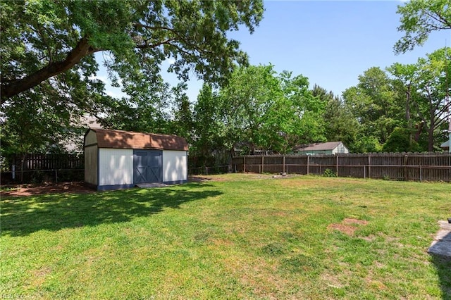 view of yard with a fenced backyard, a storage unit, and an outbuilding