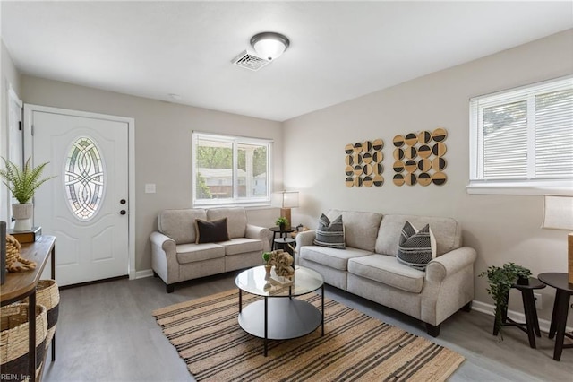 living room featuring visible vents, light wood finished floors, and baseboards