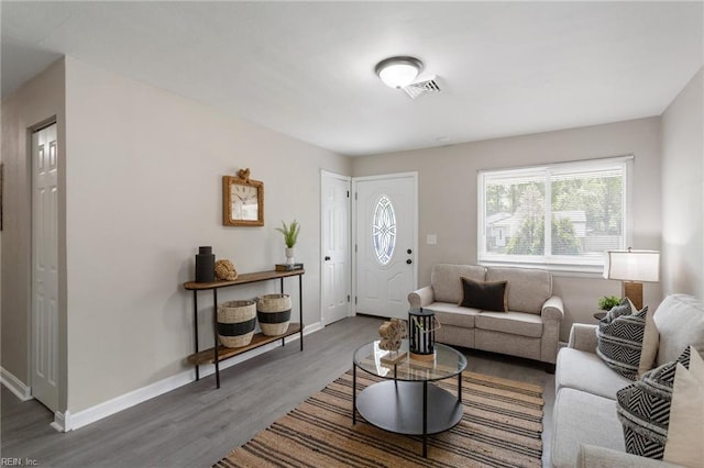 living area featuring baseboards, visible vents, and wood finished floors